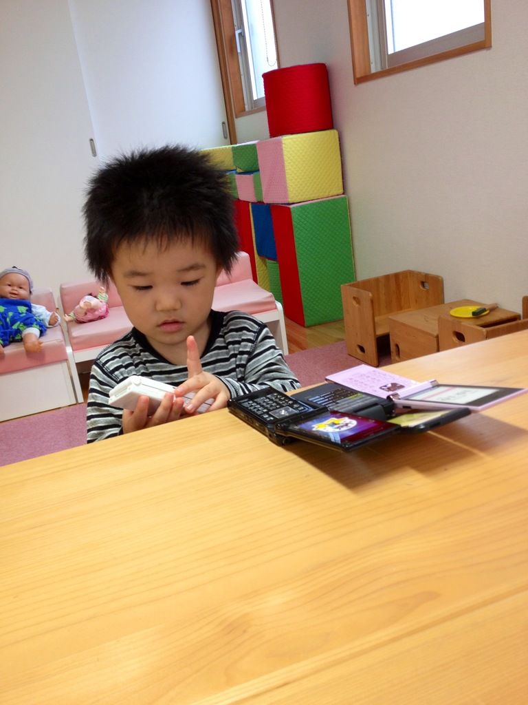 Here we can see a kid with a mobile phone in his hand and there are mobile phones placed on the...