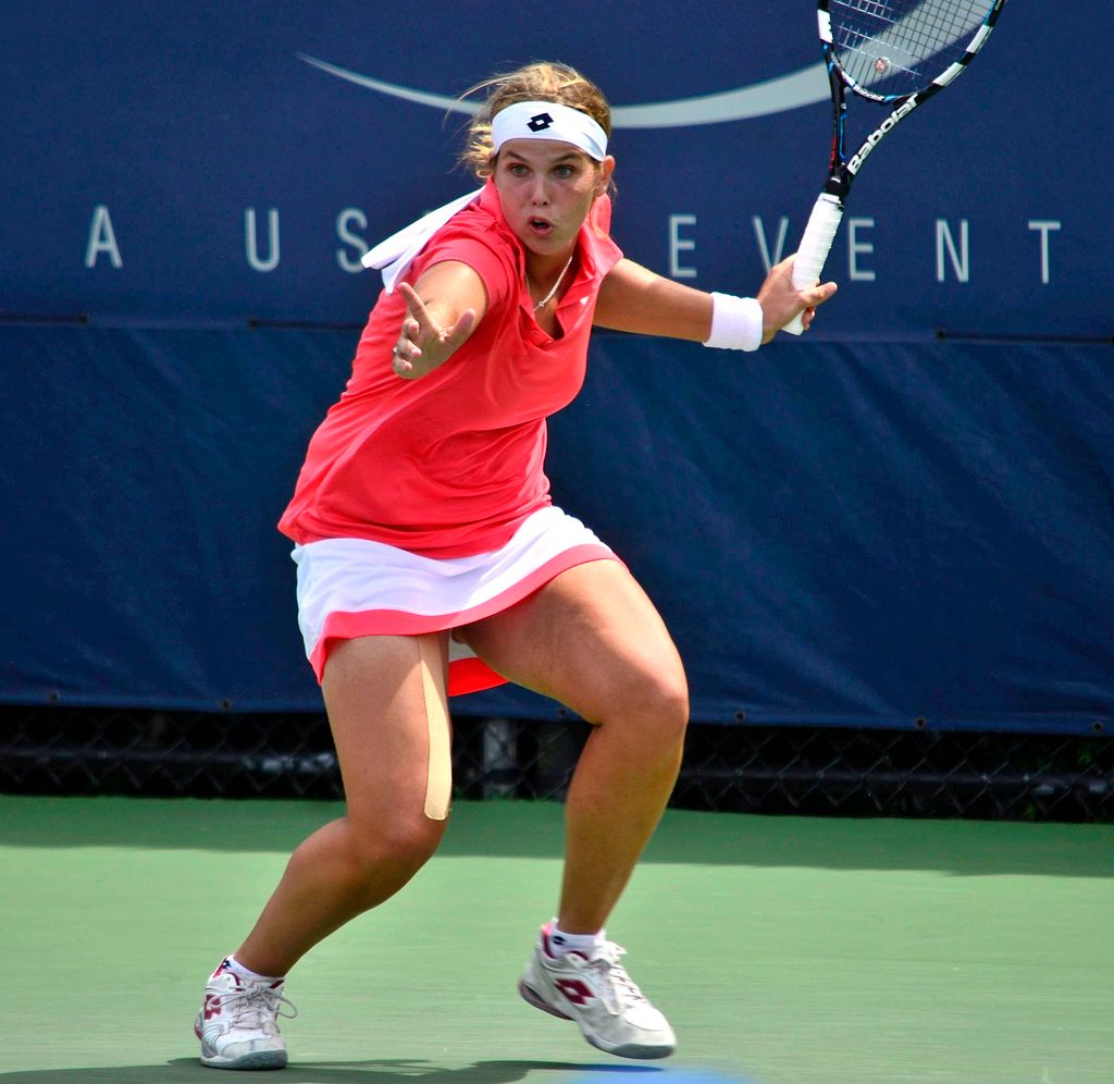 This image is clicked on the badminton ground. Here in the middle of the image there is woman who...