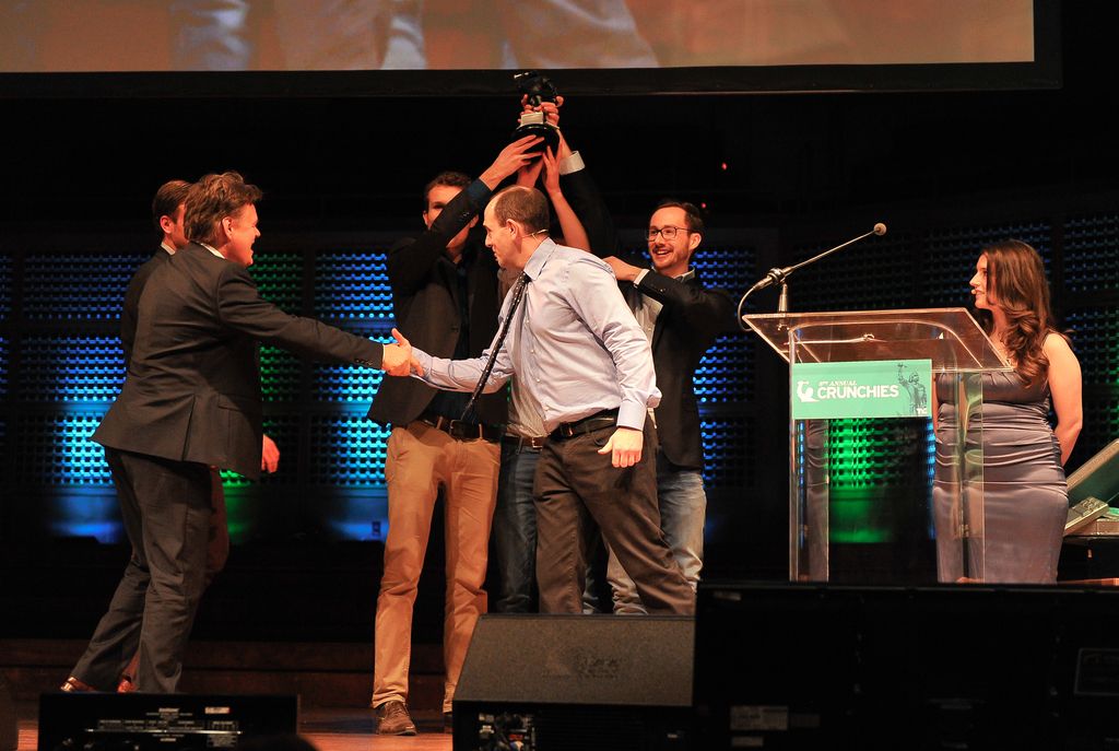 In the middle 2 men are lifting the prize with their hands and smiling. They wore black color...