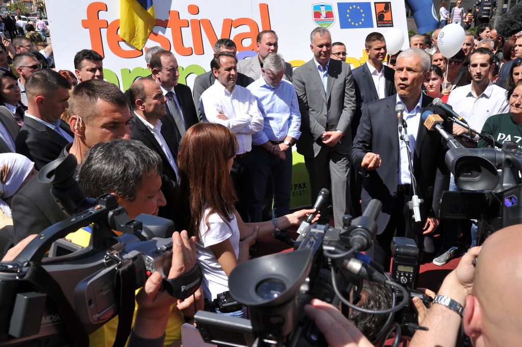 In this image I can see a group of people are standing on the road and are holding cameras in their...