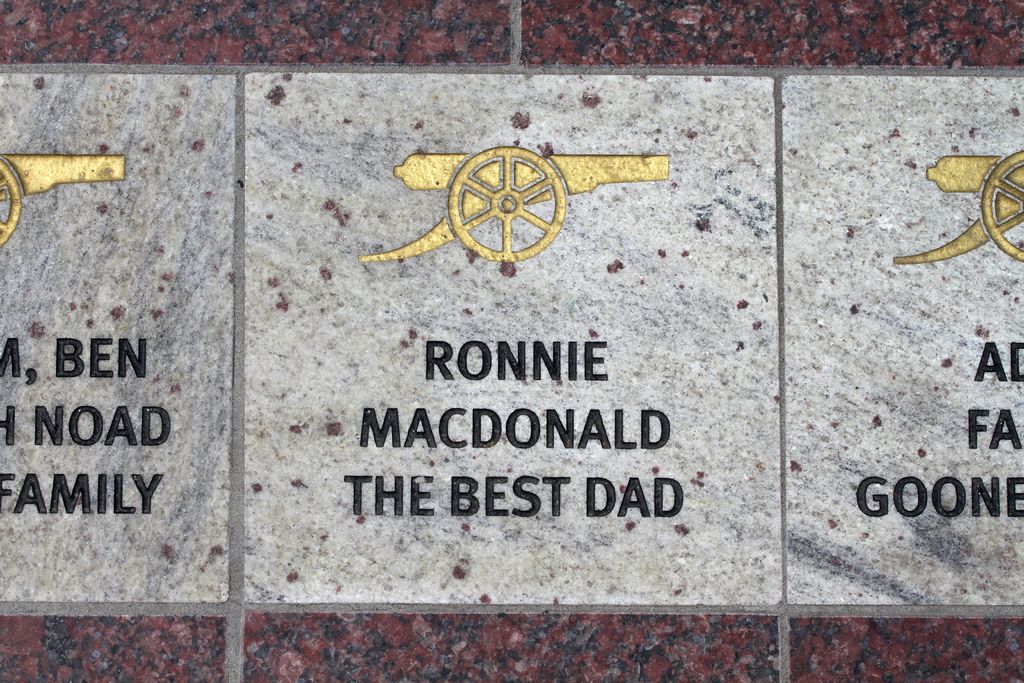 In this image I can see a historical plaque in the center of the image with some symbols and text.