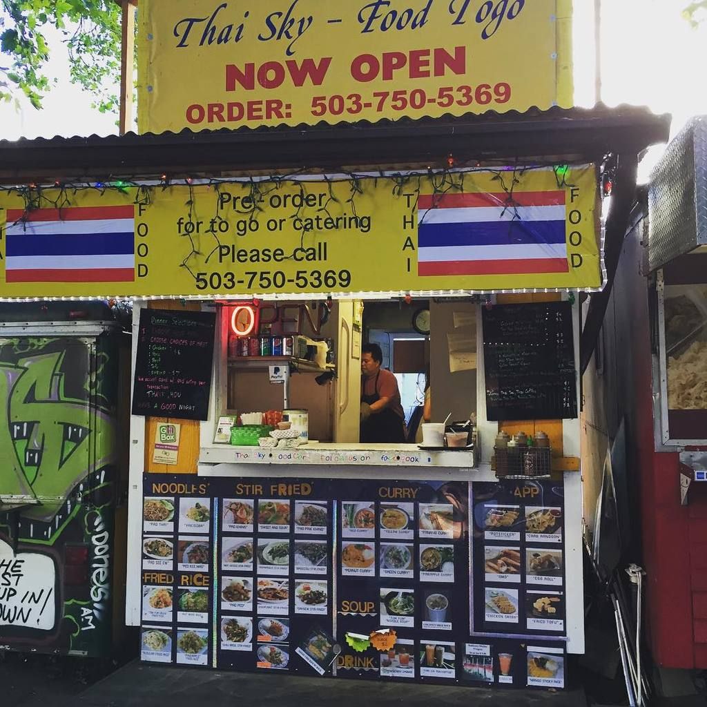 In this image we can see stores, beverage tins, menu boards, clock, spices in the plastic...