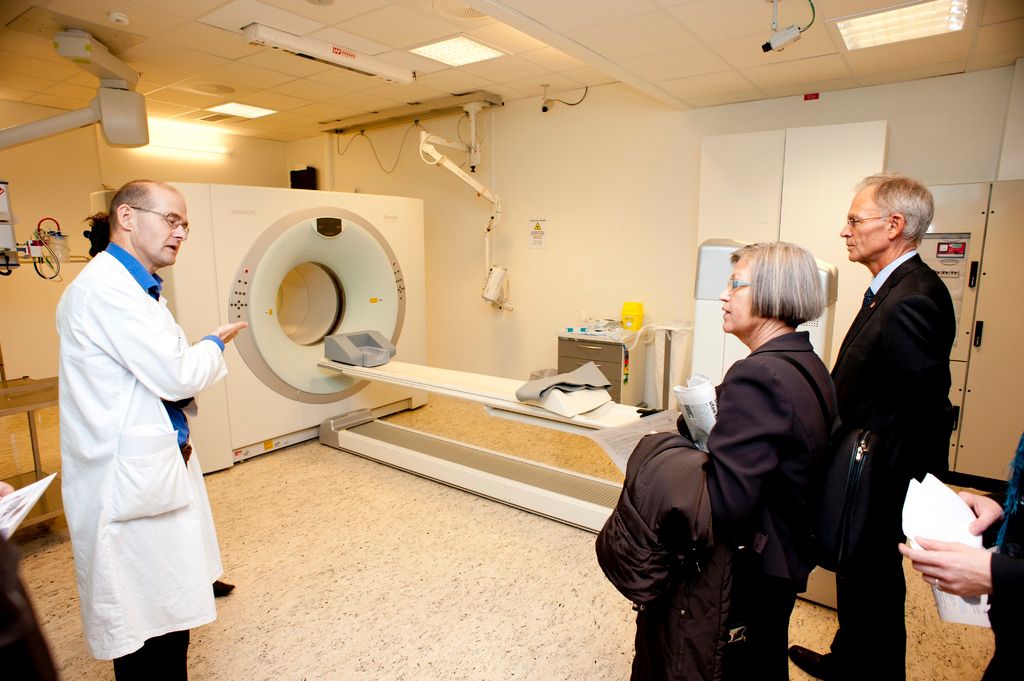 In this picture we can see the doctor in white uniform explaining about the CT scan machine to 2...