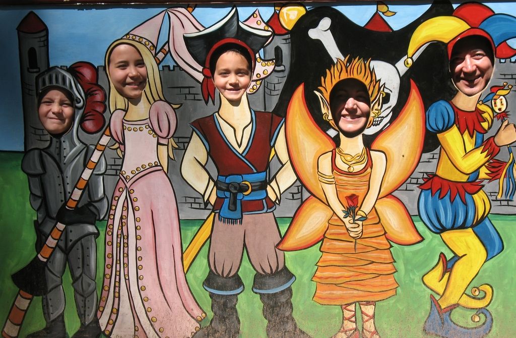 There is a big poster of different animated images and their heads are cut and few people are...