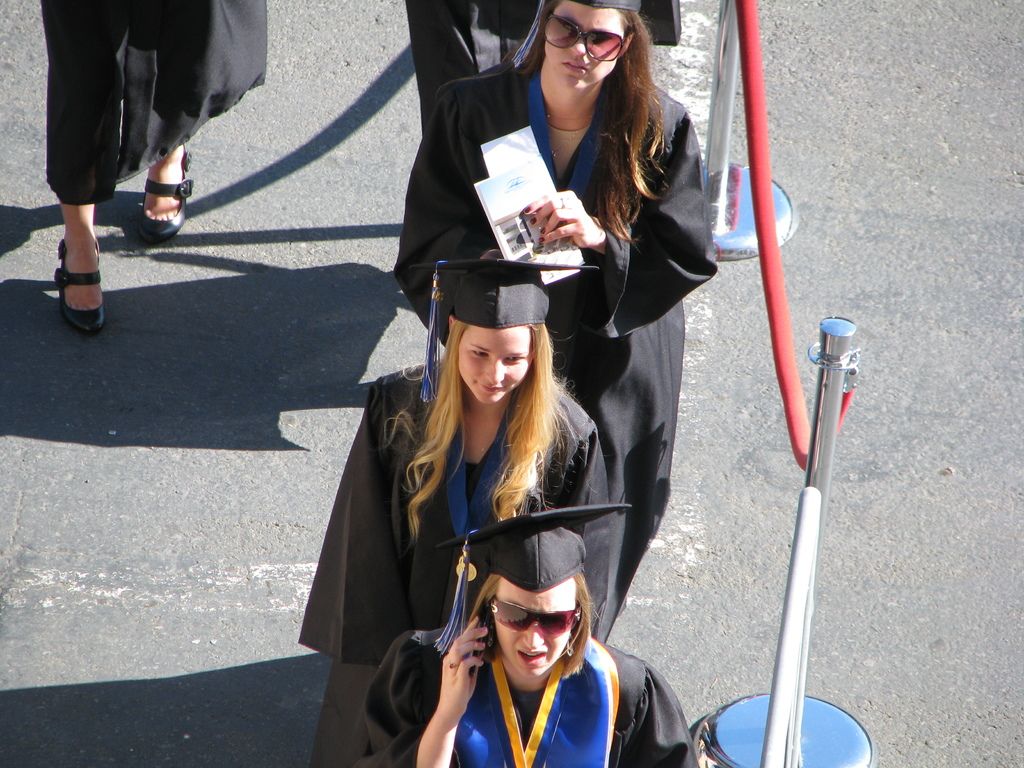 In this picture there are few women wearing graduation dress which is in black color.