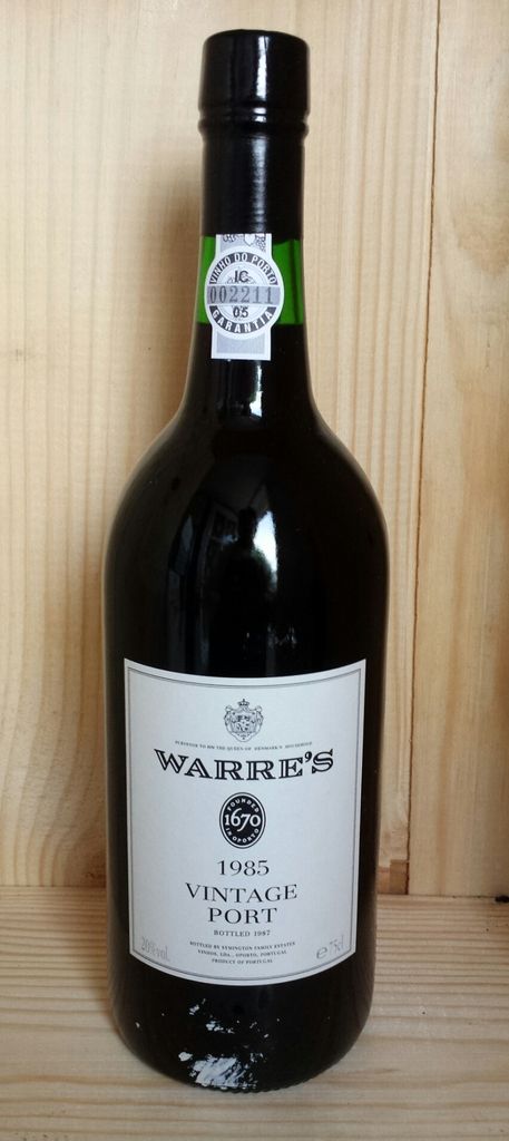 In this image there is a beer bottle with the labels on the wooden path.