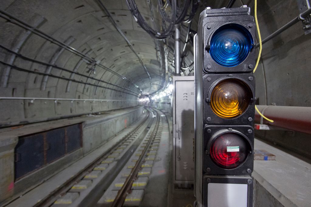 In this image we can see the track inside a subway. We can also see some wires, pipes, a container...