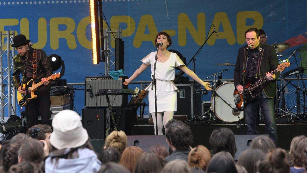 This image is clicked in a concert. There are four people performing music on the dais. In the...