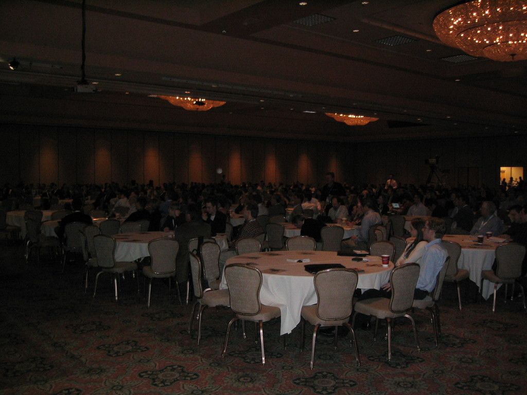 It looks like a dining hall. A group of people are sitting on the chairs around a round table.
