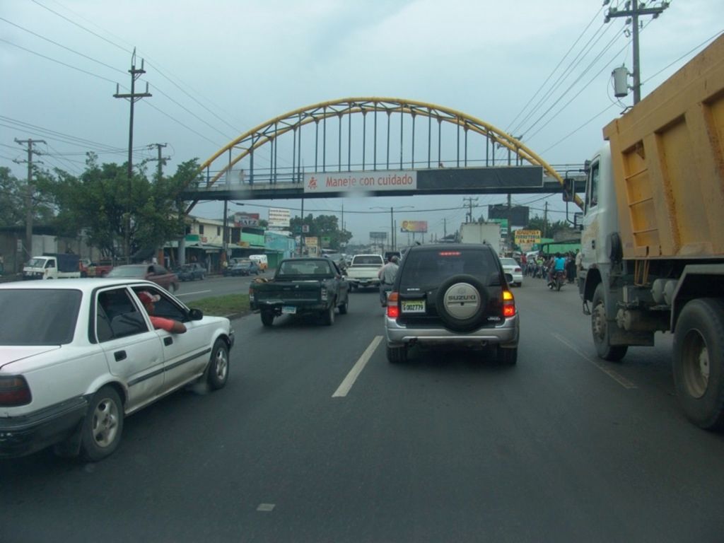 As we can see in the image there are cars, trucks, motorcycles, bridge, current polls, buildings,...