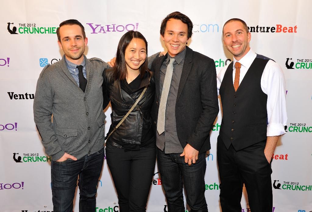 In this image there are a few people standing with a smile on their face are posing for the camera,...