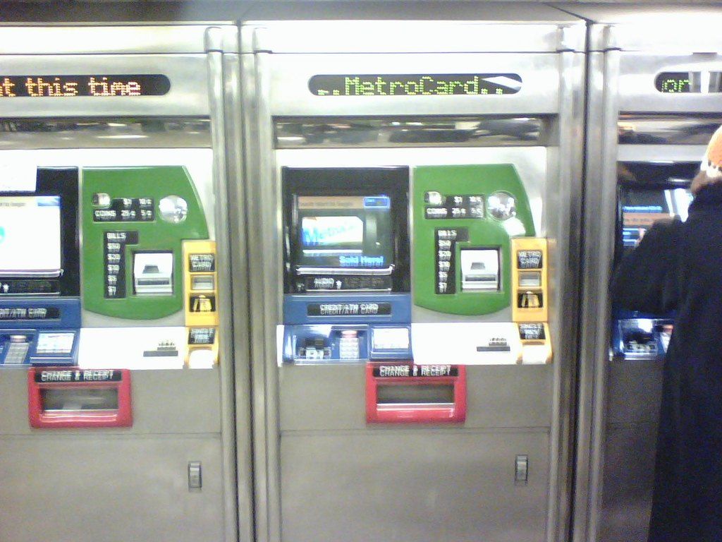 In this image we can see automatic ticket vending machines. On the right there is a person.