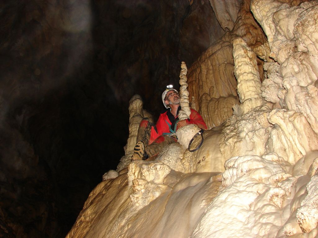 In this image there is a person sitting inside a cave.