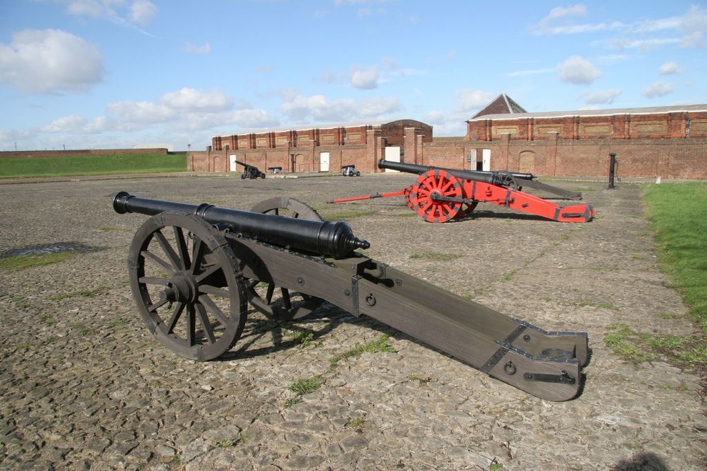 In the foreground of the picture there are cannons on cobblestone. In the foreground of the picture...