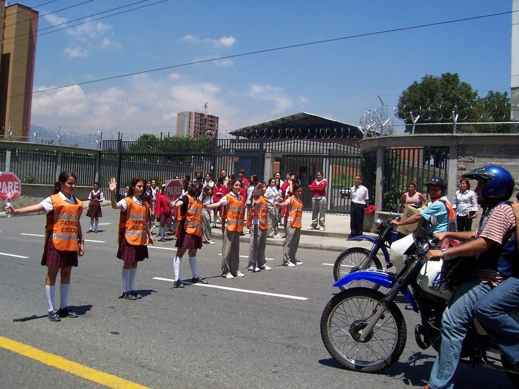 This picture is taken on road. There are many people on the road. The are school girls wearing...