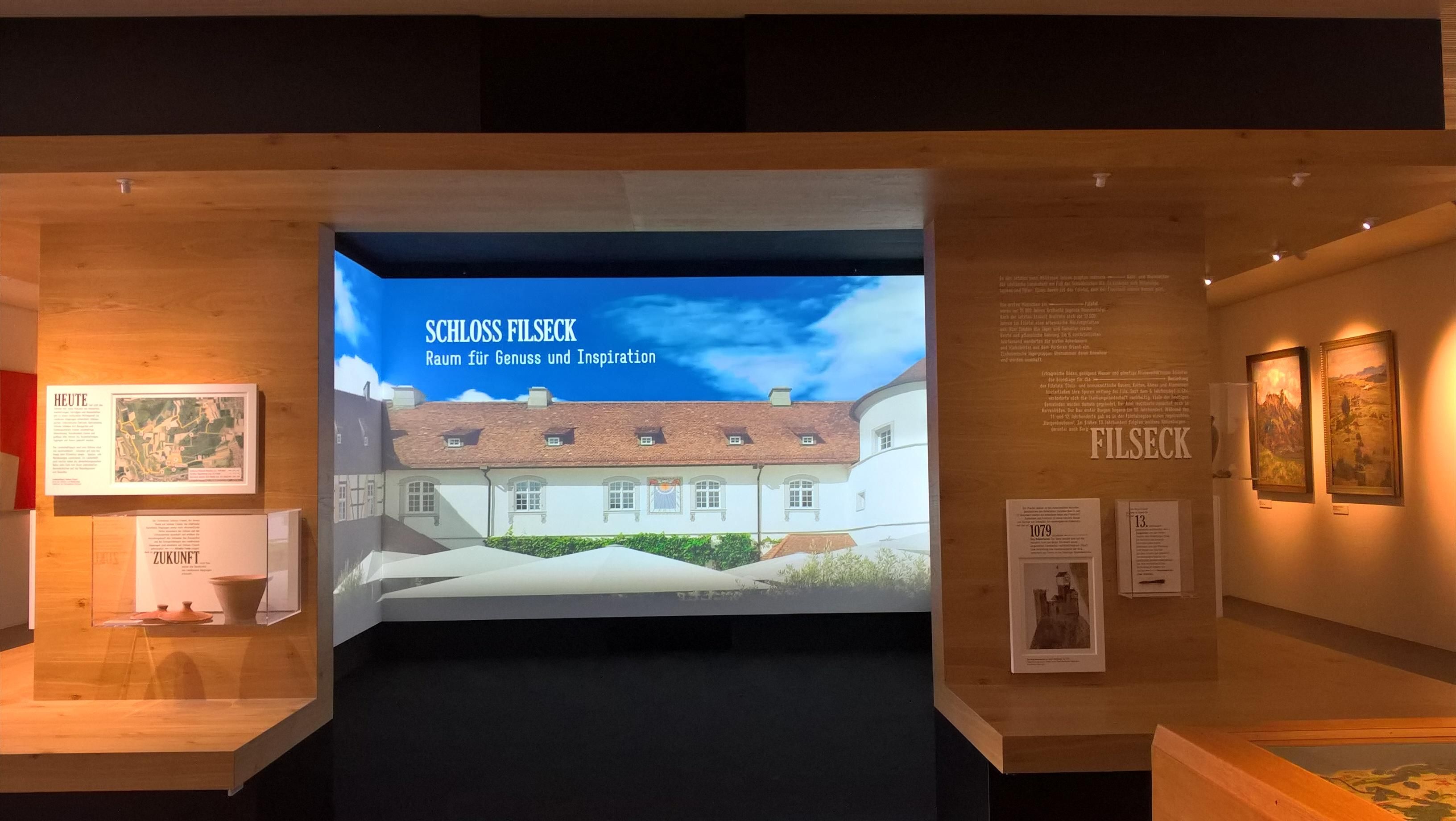 The image shows a room filled with lots of different types of art on display, including photo...