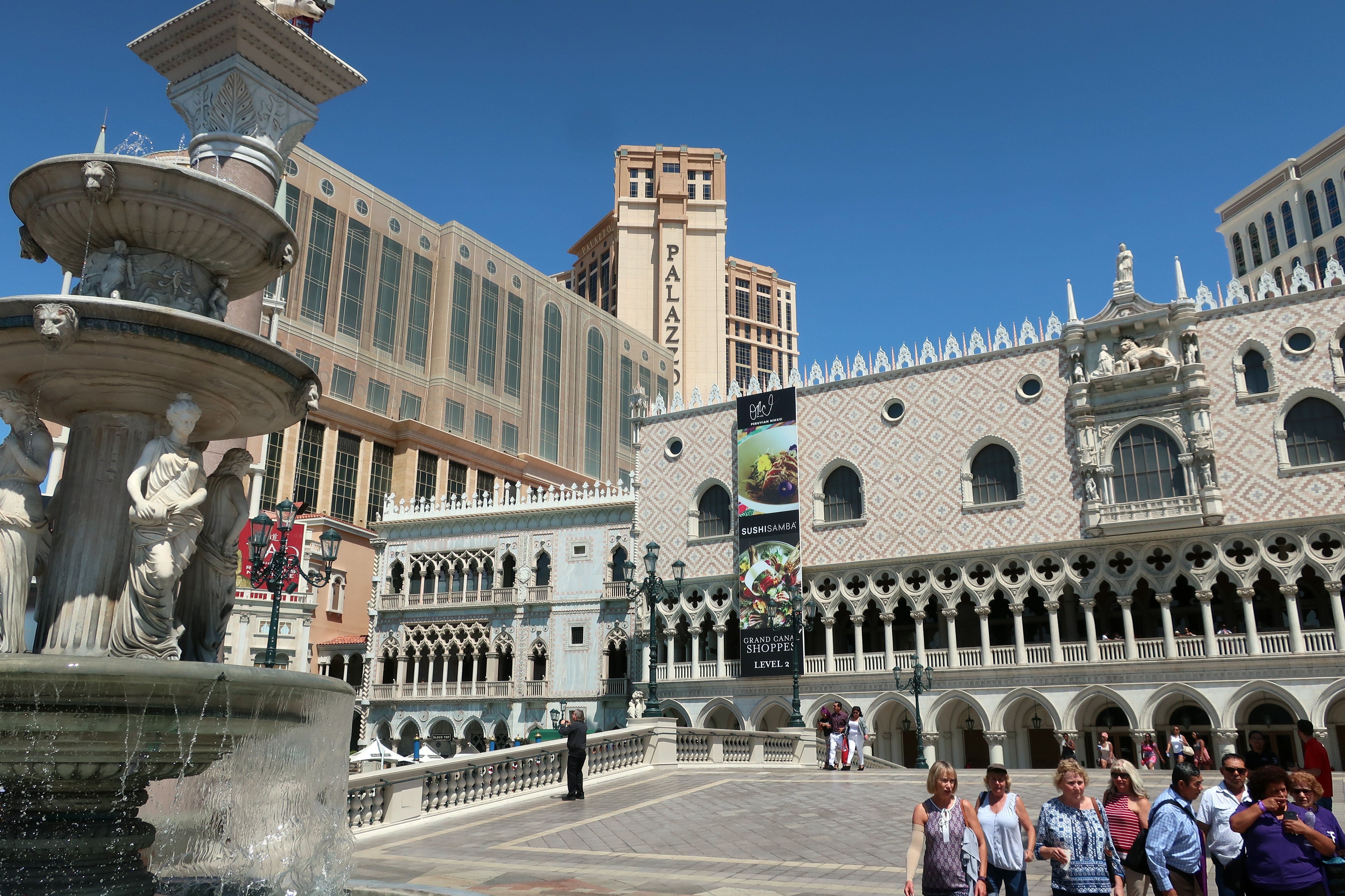 The image shows the Venetian Hotel and Casino in Las Vegas, Nevada. There are many people walking...