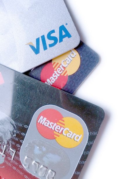 The image shows three credit cards stacked on top of each other on a white surface. The cards are...