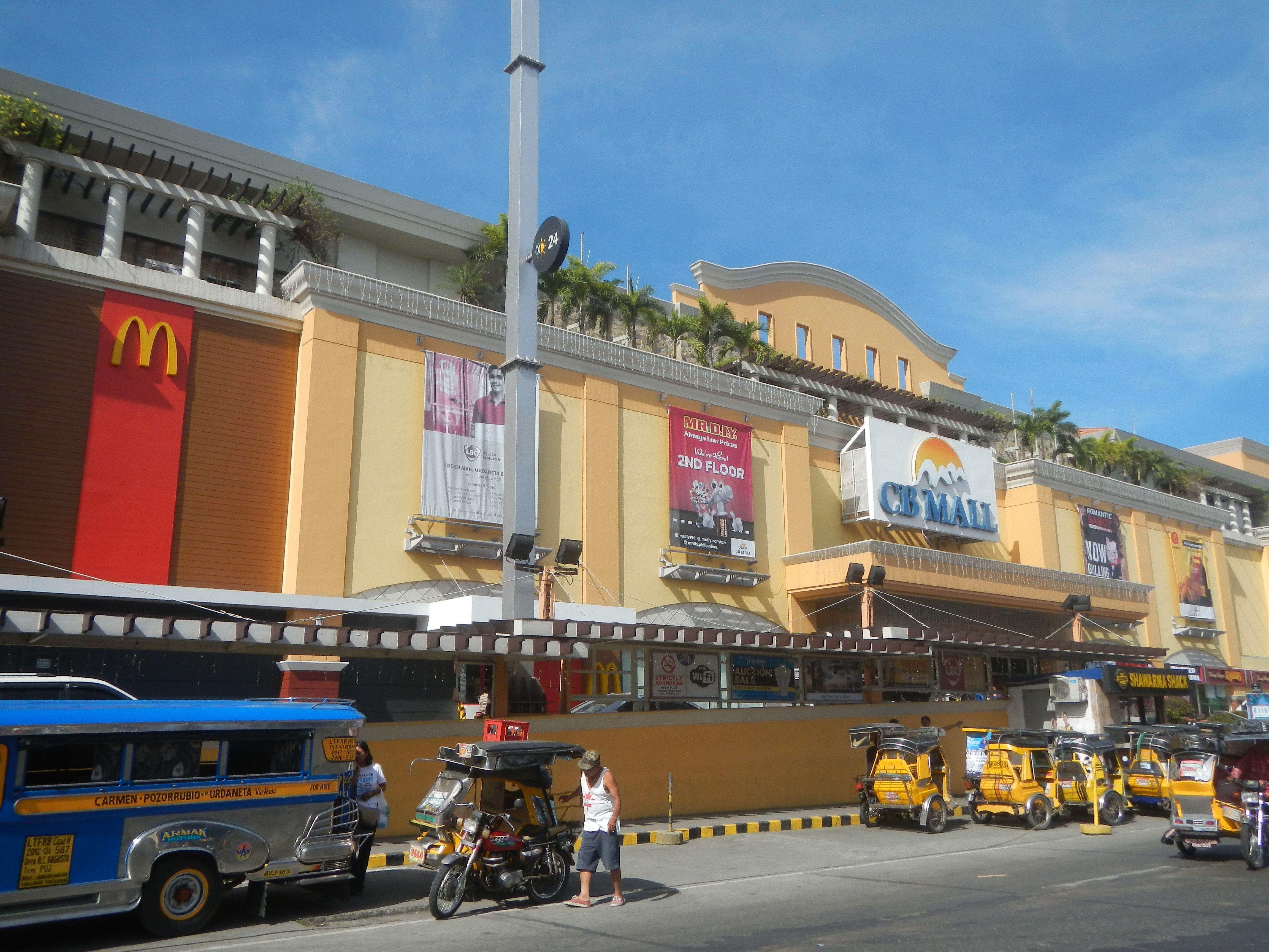The image shows a bustling street in Cebu City, Philippines, with a variety of vehicles and people...