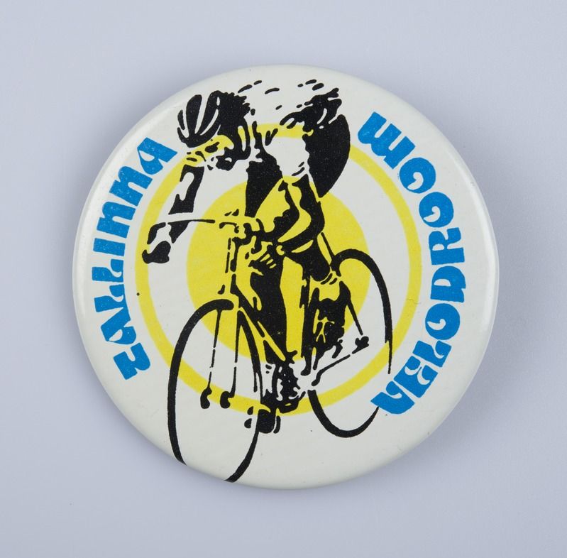 The image shows a white badge with a picture of a man riding a bicycle on it, with the words...
