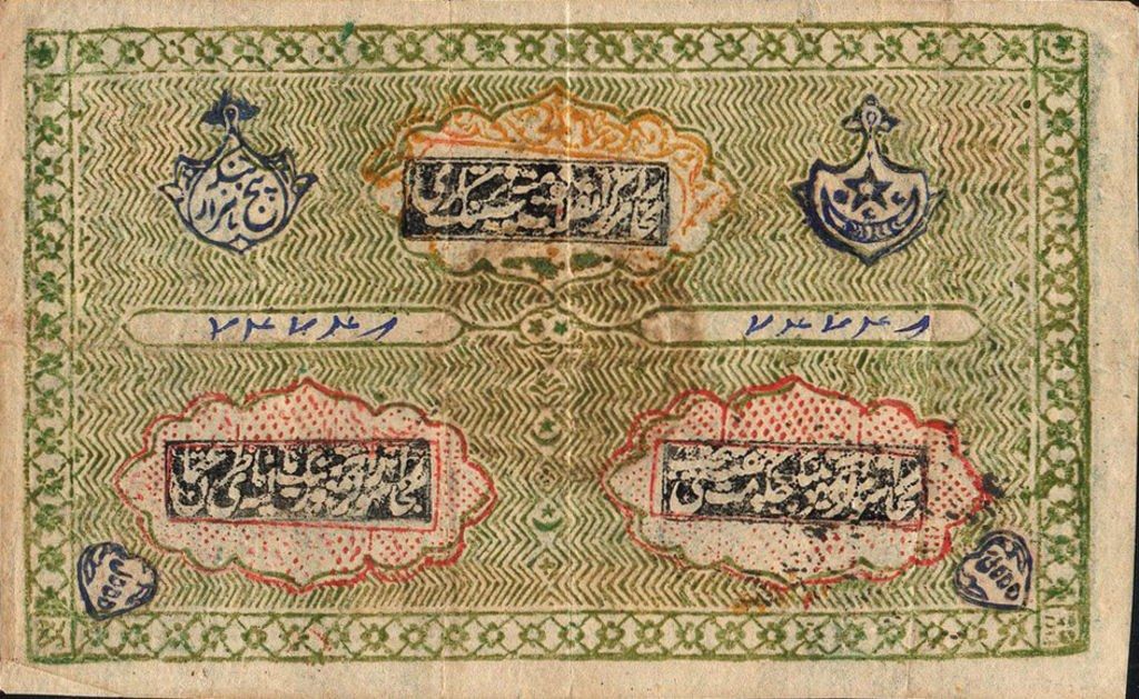 The image shows an old banknote with Arabic writing on it against a black background. The text on...