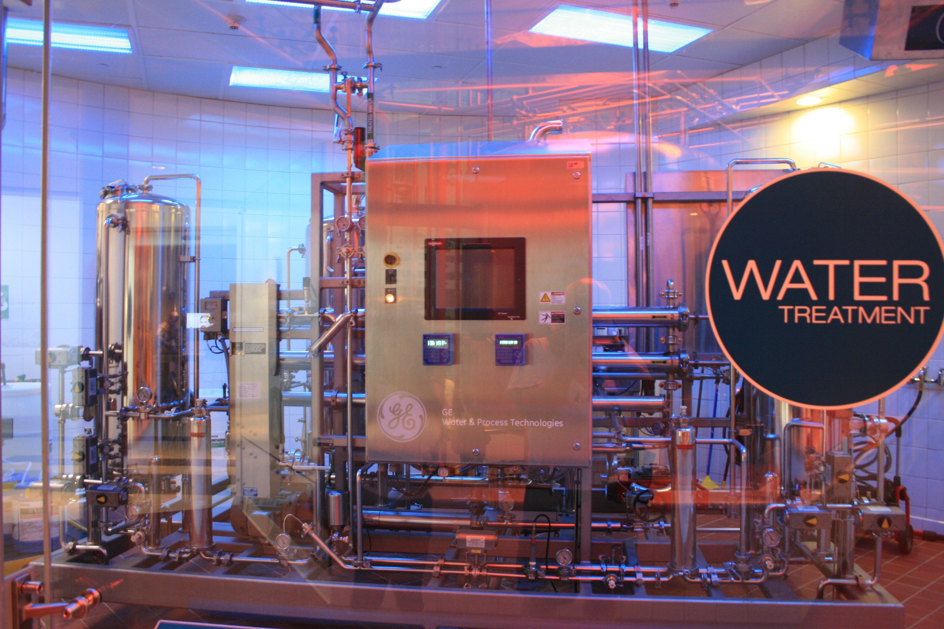 The image shows a large machine inside of a building with a sign that reads "Water Treatment" on...