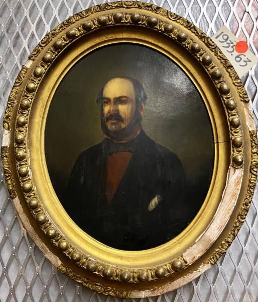 The image shows a portrait of a man in a black suit and bow tie, painted in oil on canvas, hanging...