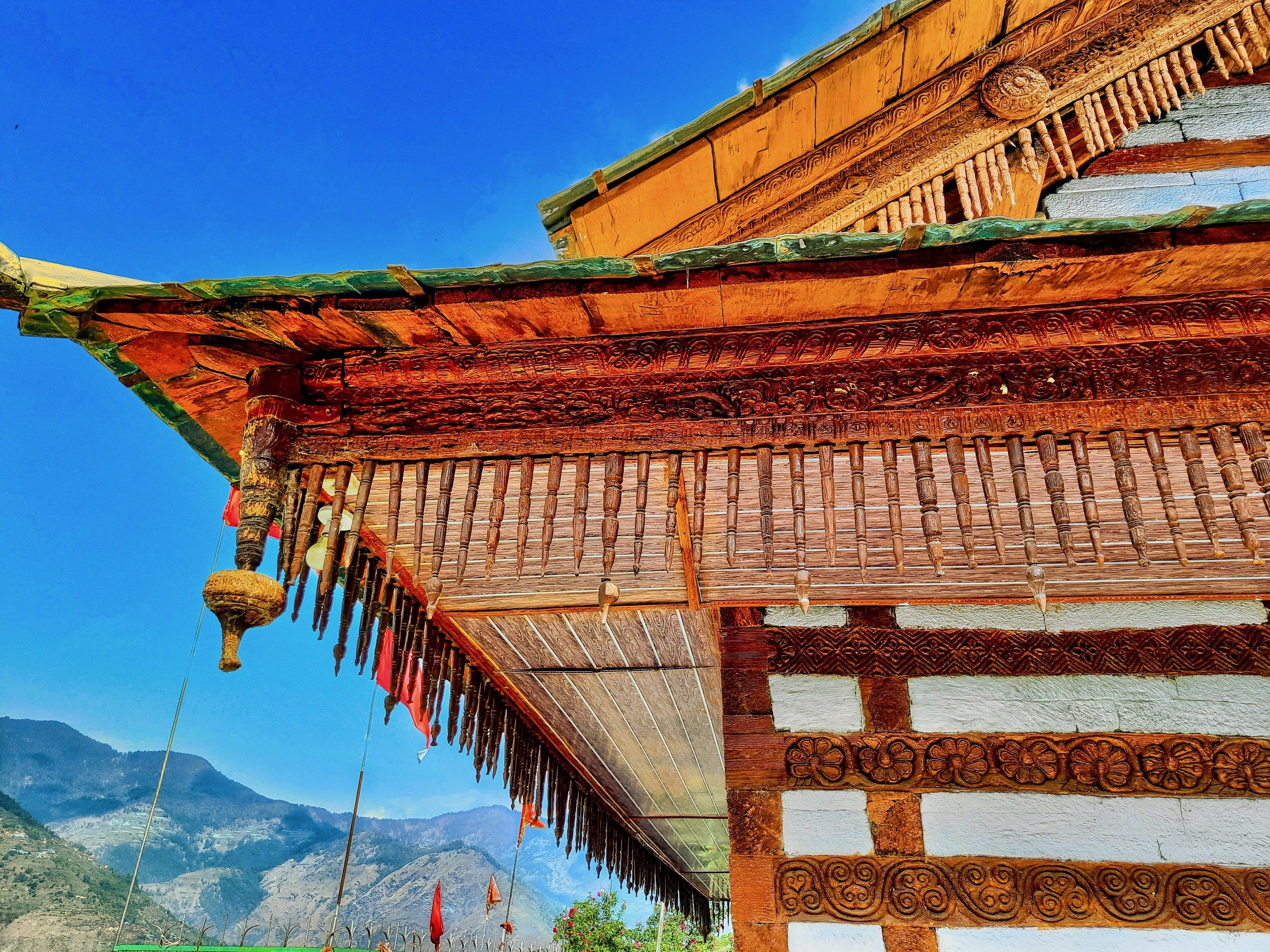 The image shows a Buddhist temple in Bhutan with a roof adorned with intricate designs, surrounded...
