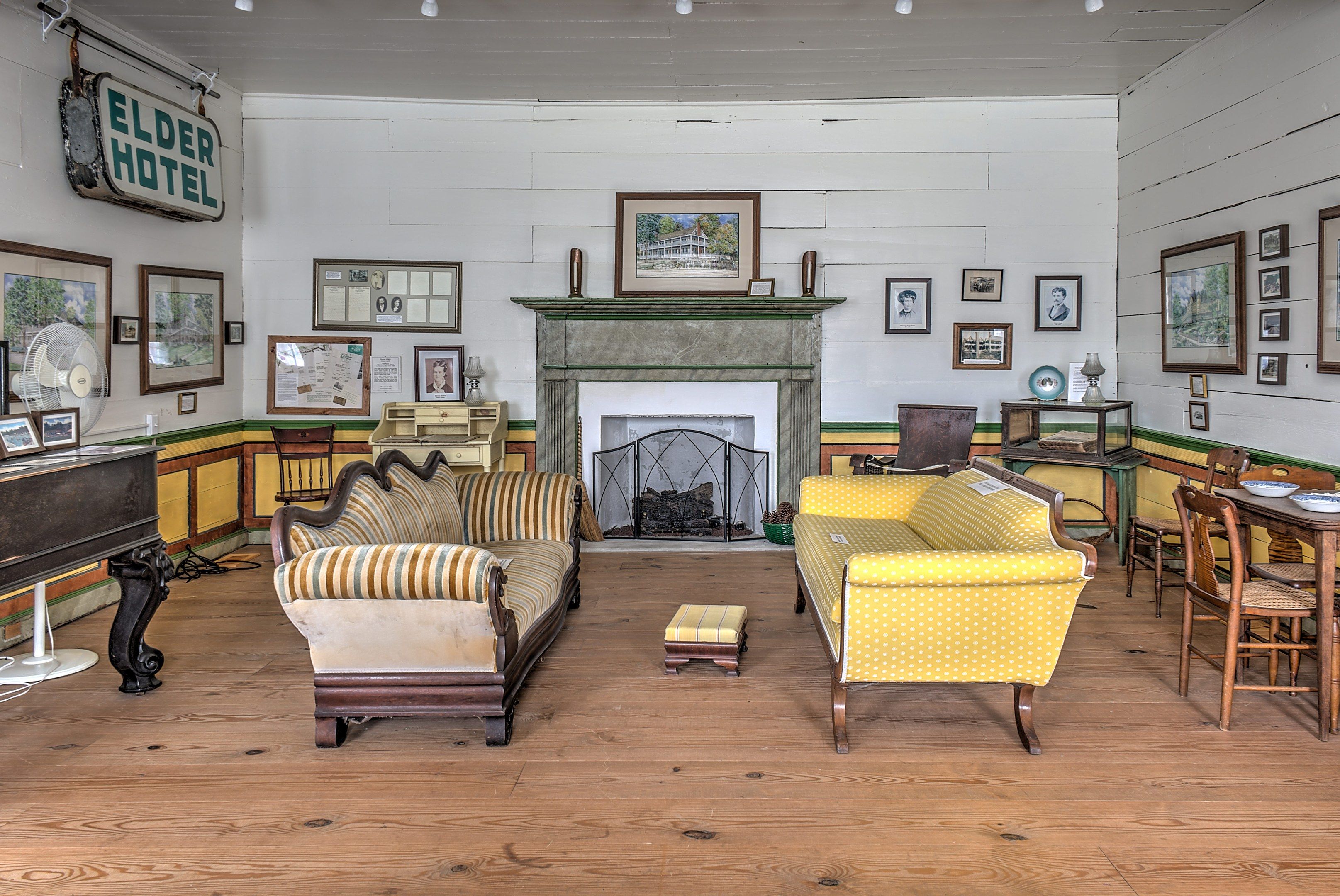 The image shows a living room filled with furniture such as sofas, chairs, tables, and a piano, as...