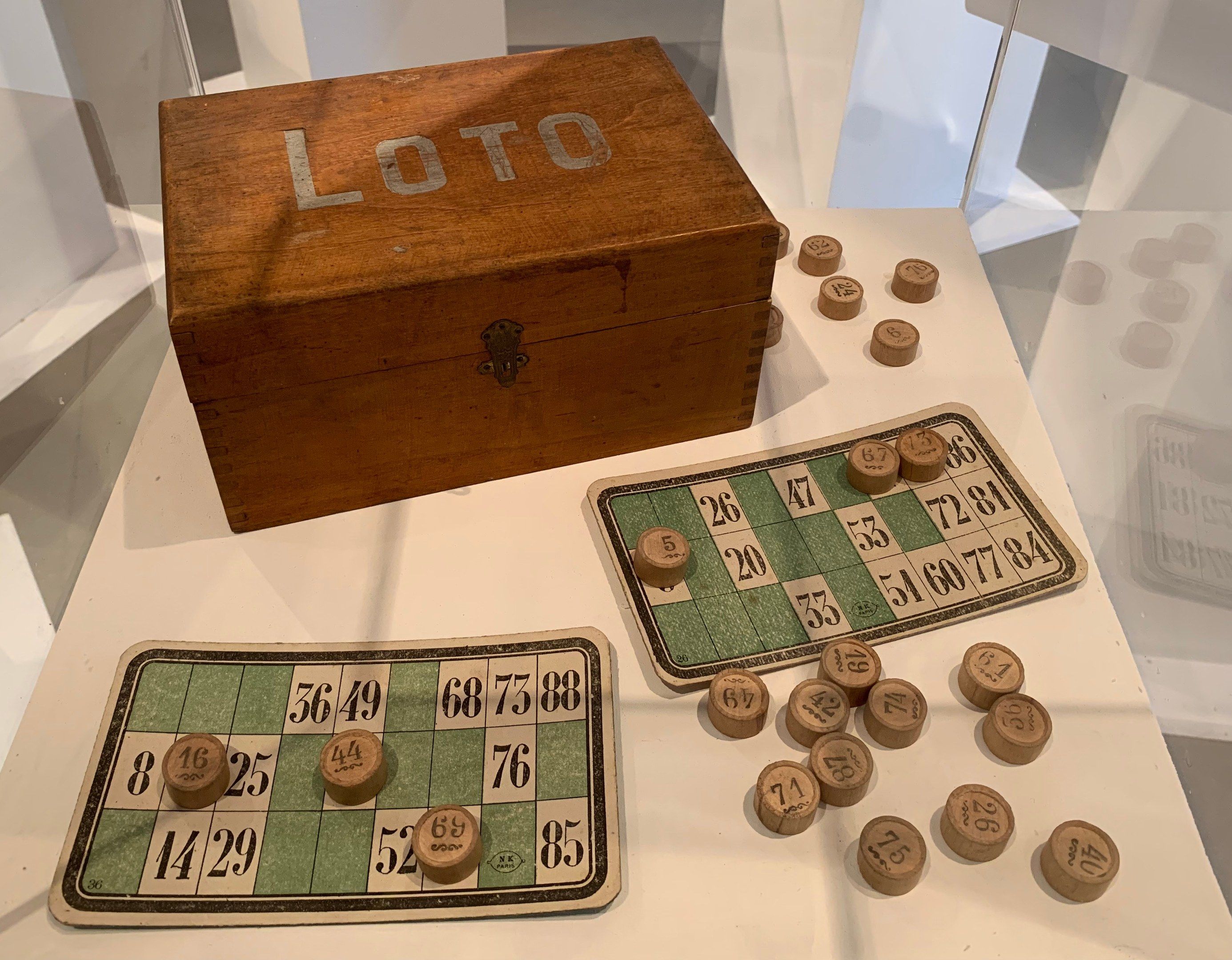 The image shows a wooden box with the word "Loto" on it, sitting on a table with a board and some...