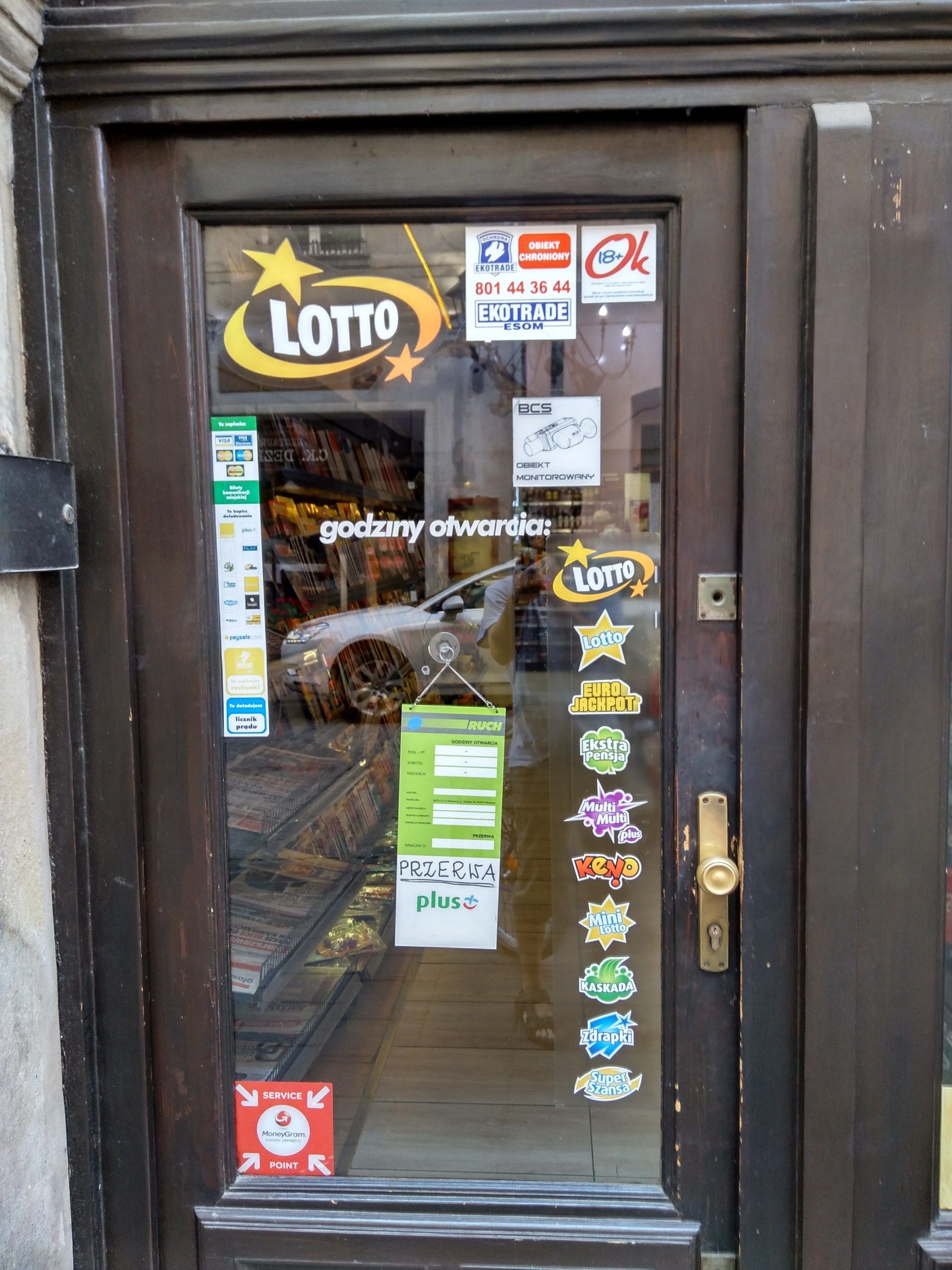 The image shows a store front with a glass door adorned with stickers and a sign that reads...