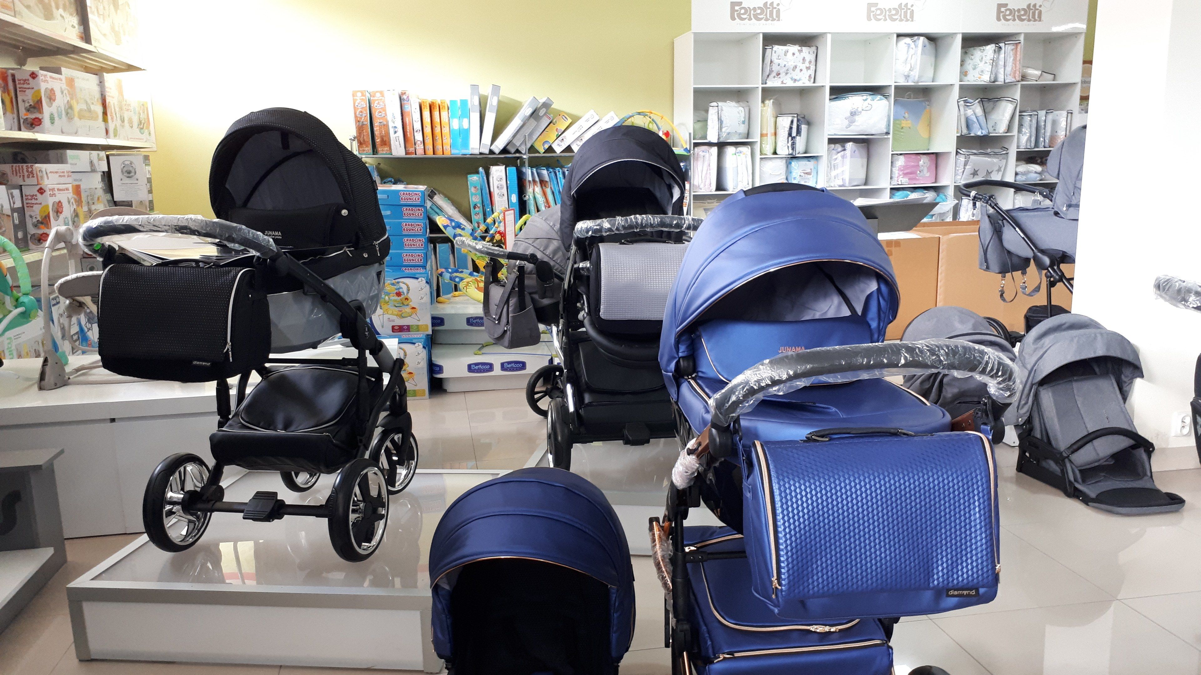 The image shows a store with a variety of baby strollers on display, including a car seat and a...