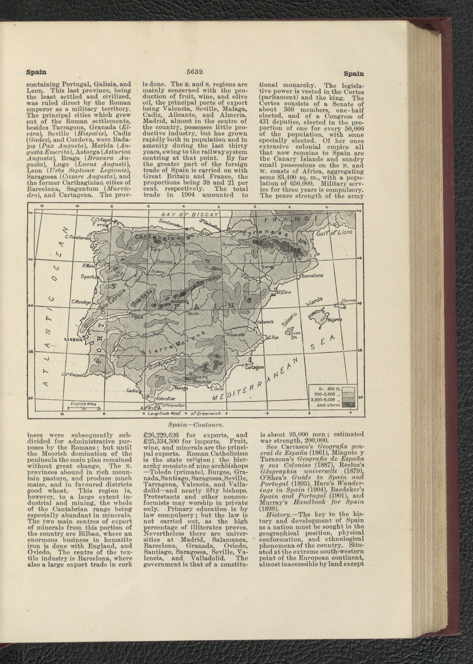 The image shows an open book with a map of Spain on it, placed on a black surface. The book...