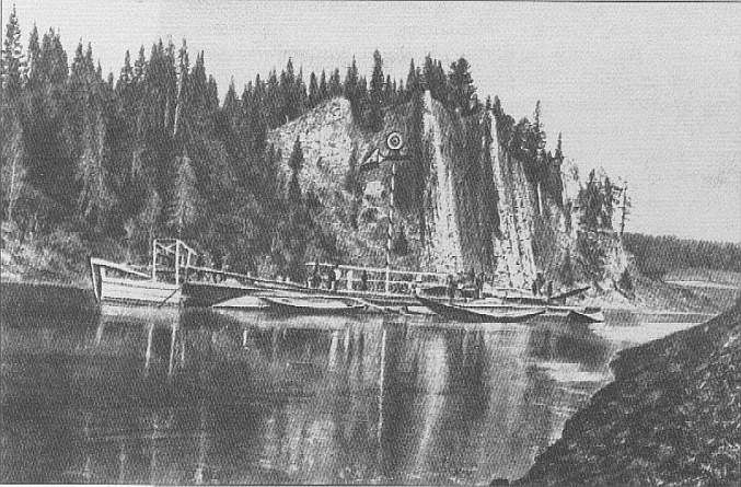 The image shows a black and white drawing of a boat docked in the water near a rocky shoreline,...