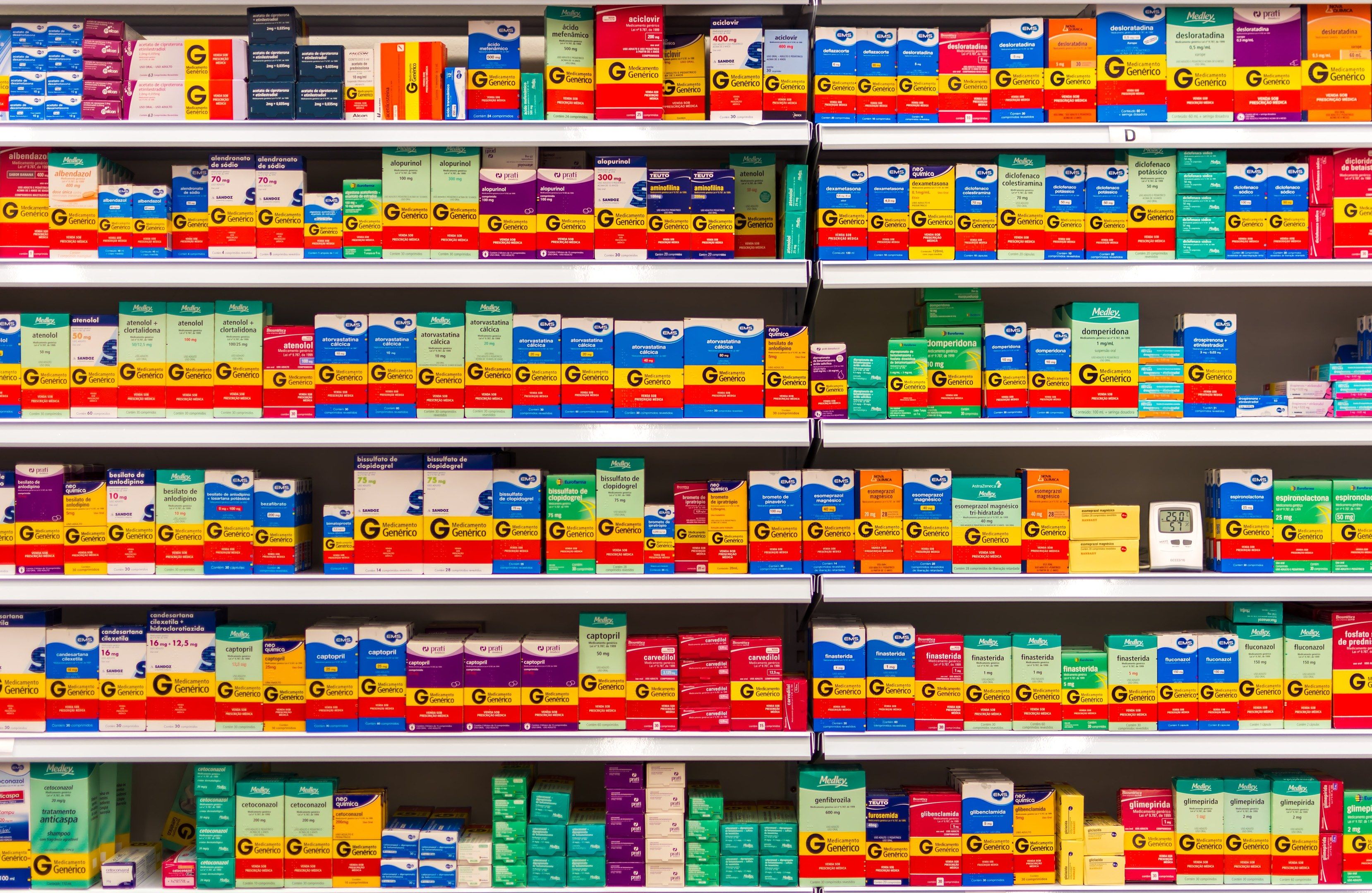 The image shows a pharmacy shelf filled with lots of different types of medicines, including boxes...