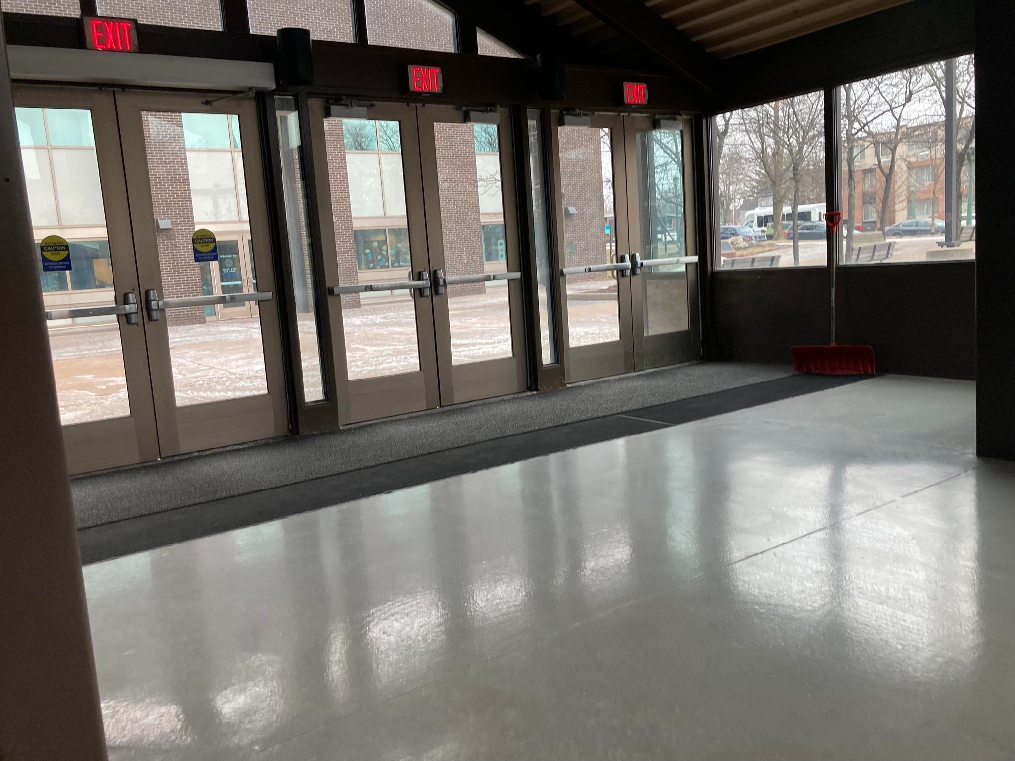 The image shows a large room with a lot of windows and doors, a broomstick on the floor, sign...