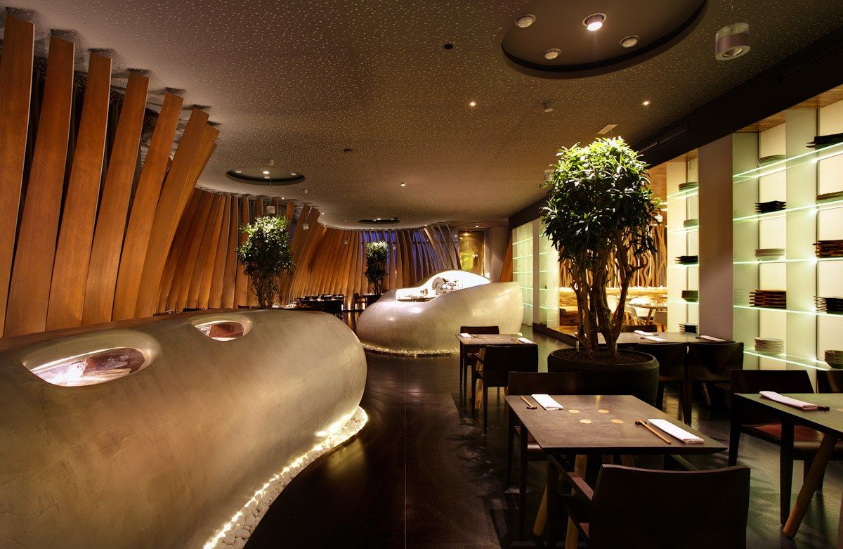 The image shows a restaurant with tables and chairs in front of a large window, surrounded by...