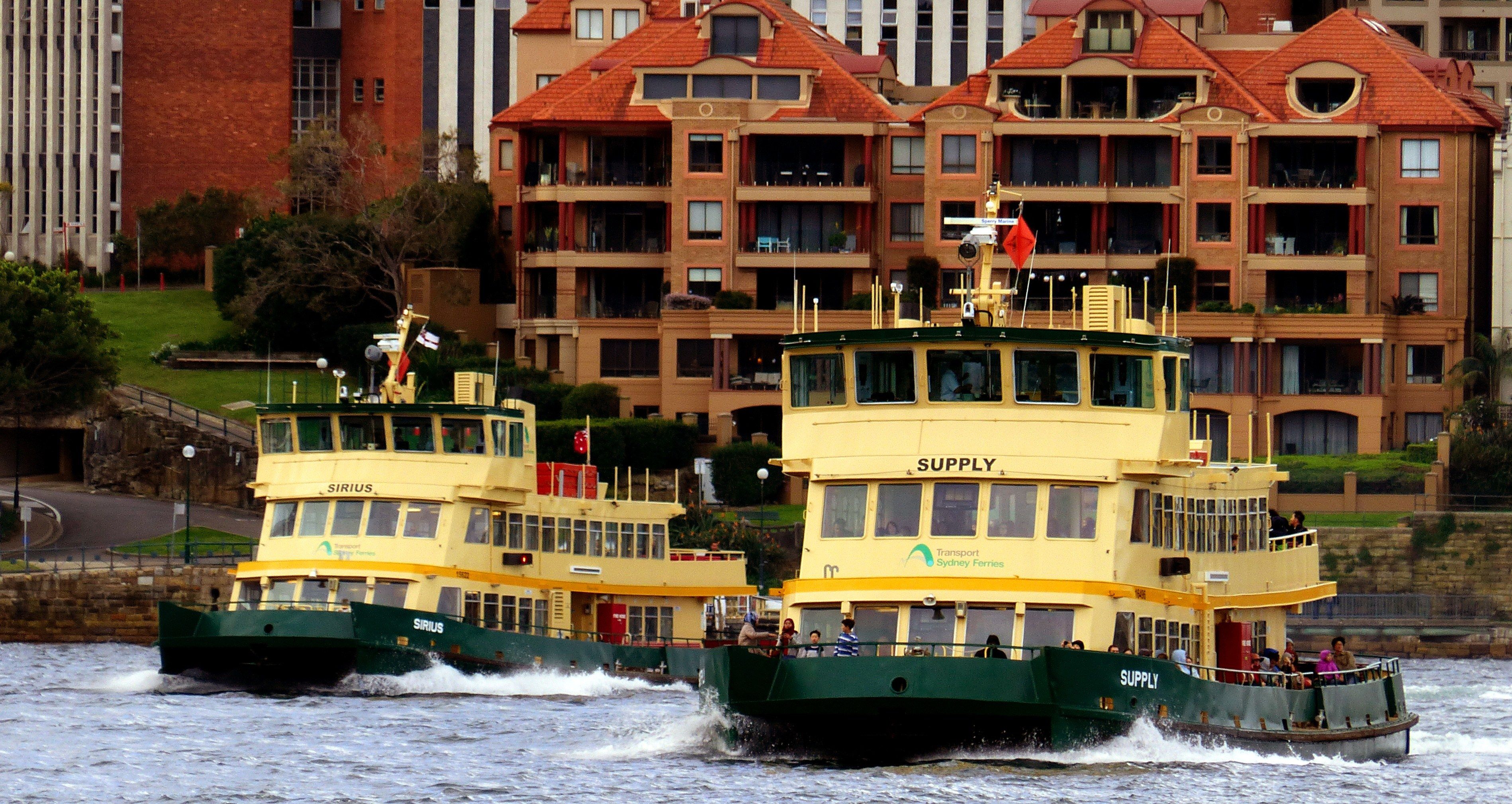 The image shows two large yellow and green boats traveling down a river, with people on board. In...