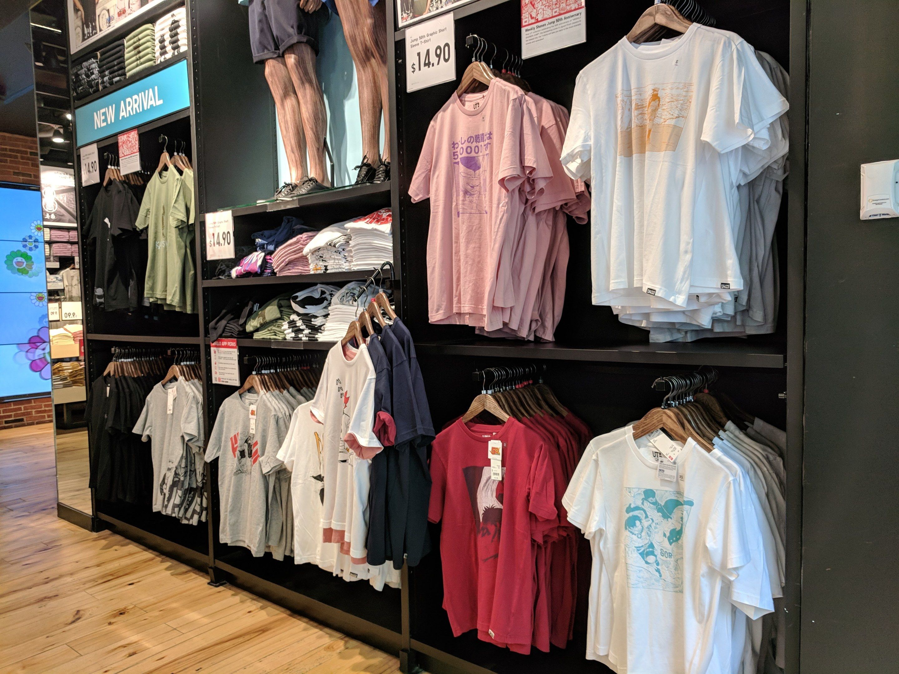 The image shows a store filled with lots of t-shirts on display, with hangers and boards with text...