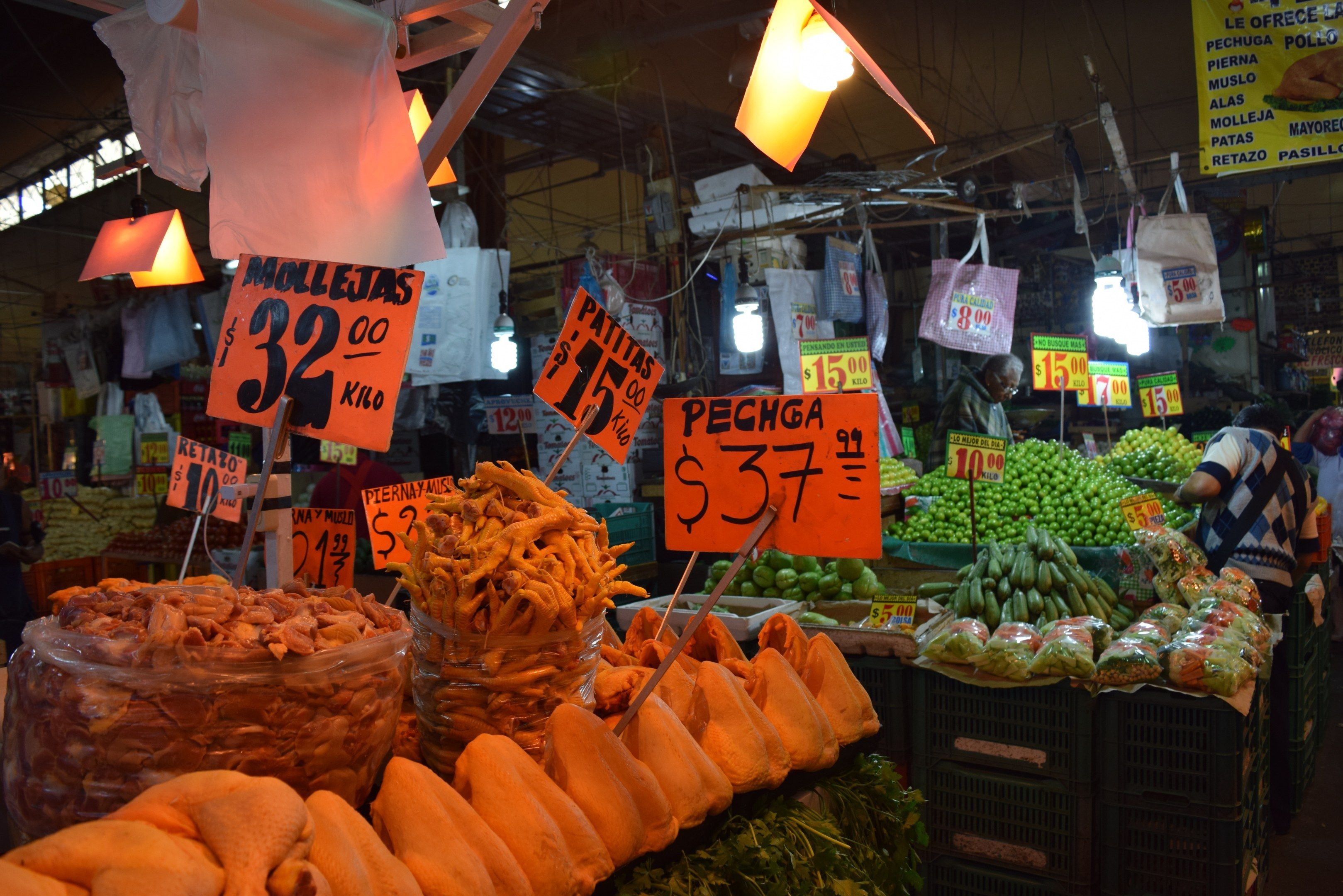 The image shows a bustling market with a variety of fruits and vegetables on display. There are...