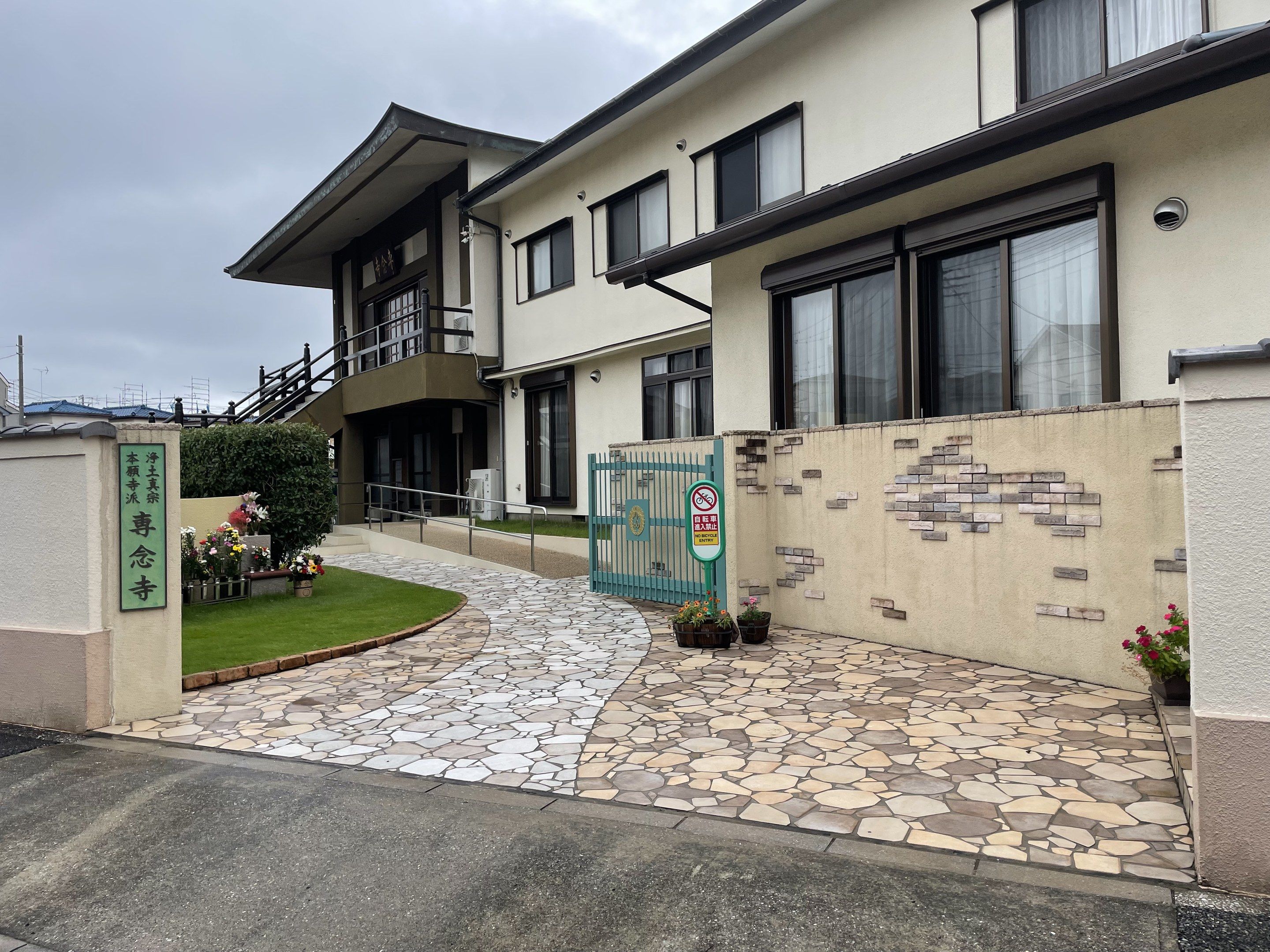 The image shows the entrance to a building with a stone walkway leading up to it, surrounded by...