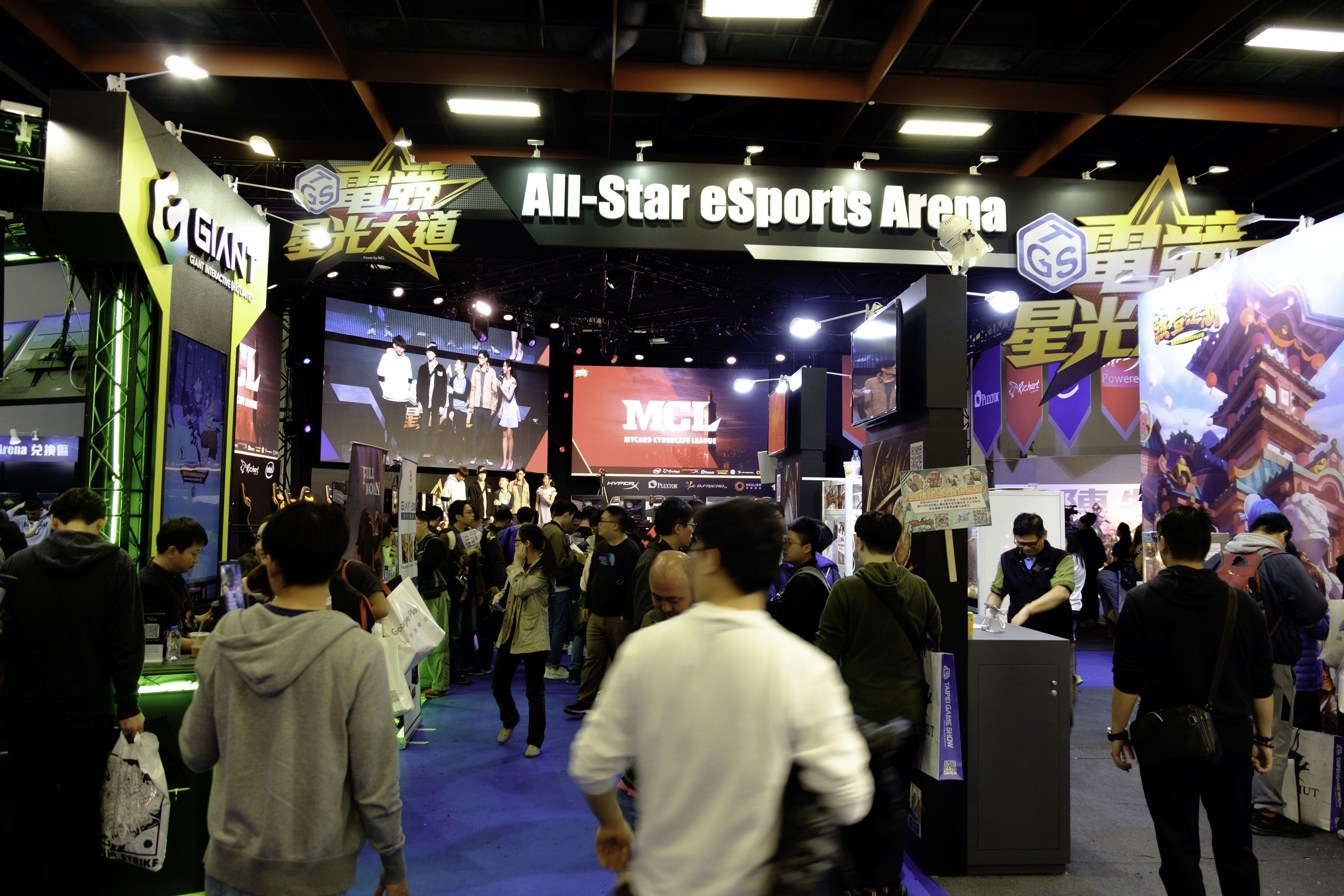 The image shows a large group of people standing in front of a booth at an all-star esports arena....