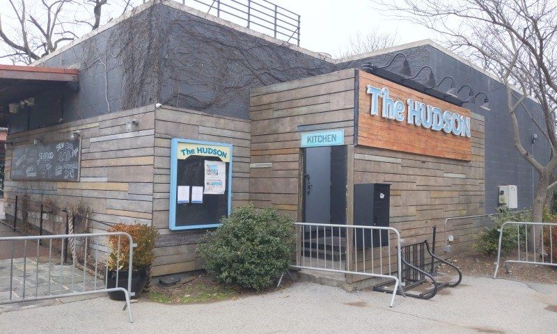 The image shows the Hudson restaurant in New York City. It is a building with a door and a board...