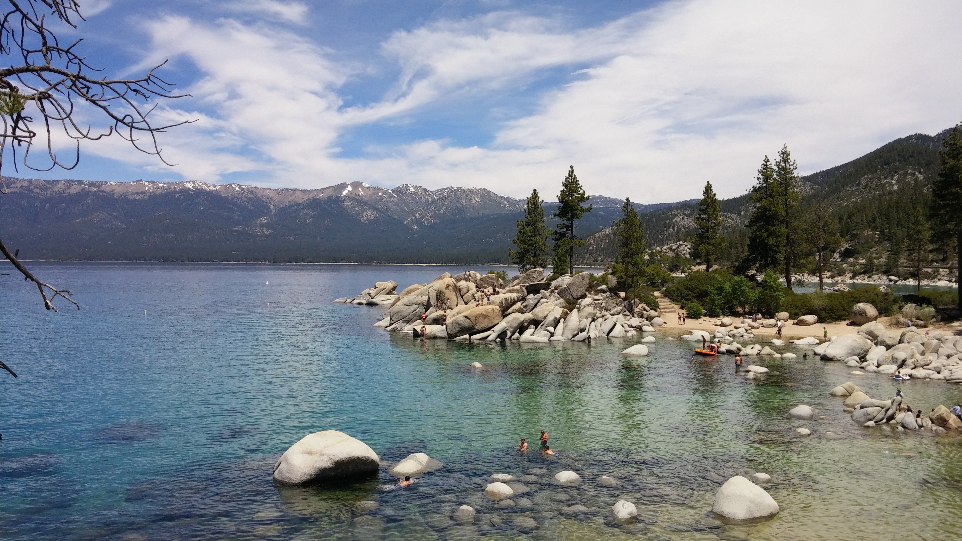 The image shows a stunning view of Lake Tahoe in California, with people swimming in the crystal...