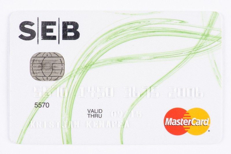 The image shows a white Mastercard with a green and white design on it against a white background....