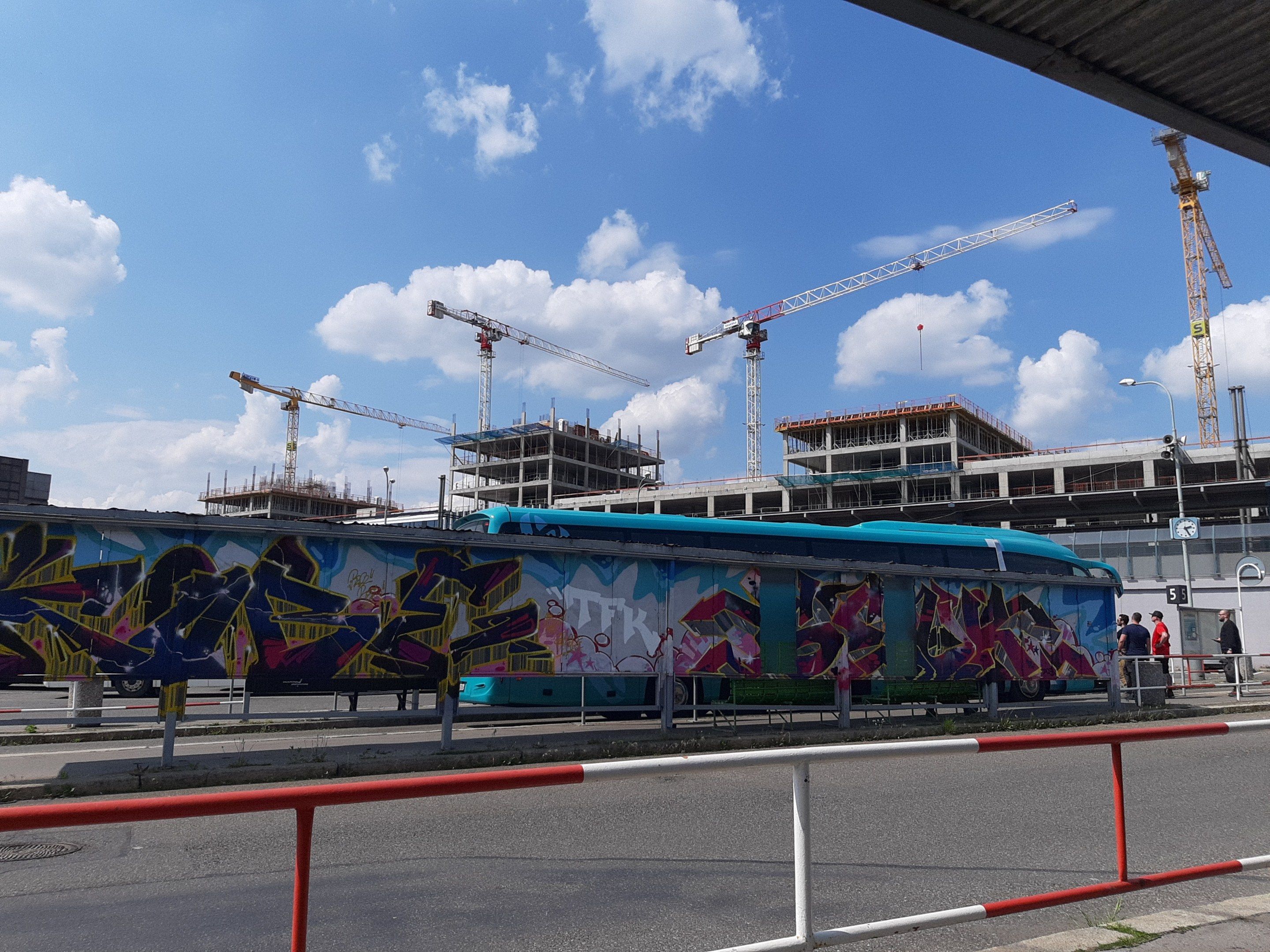 The image shows a train with graffiti on the side of it parked in front of a building under...