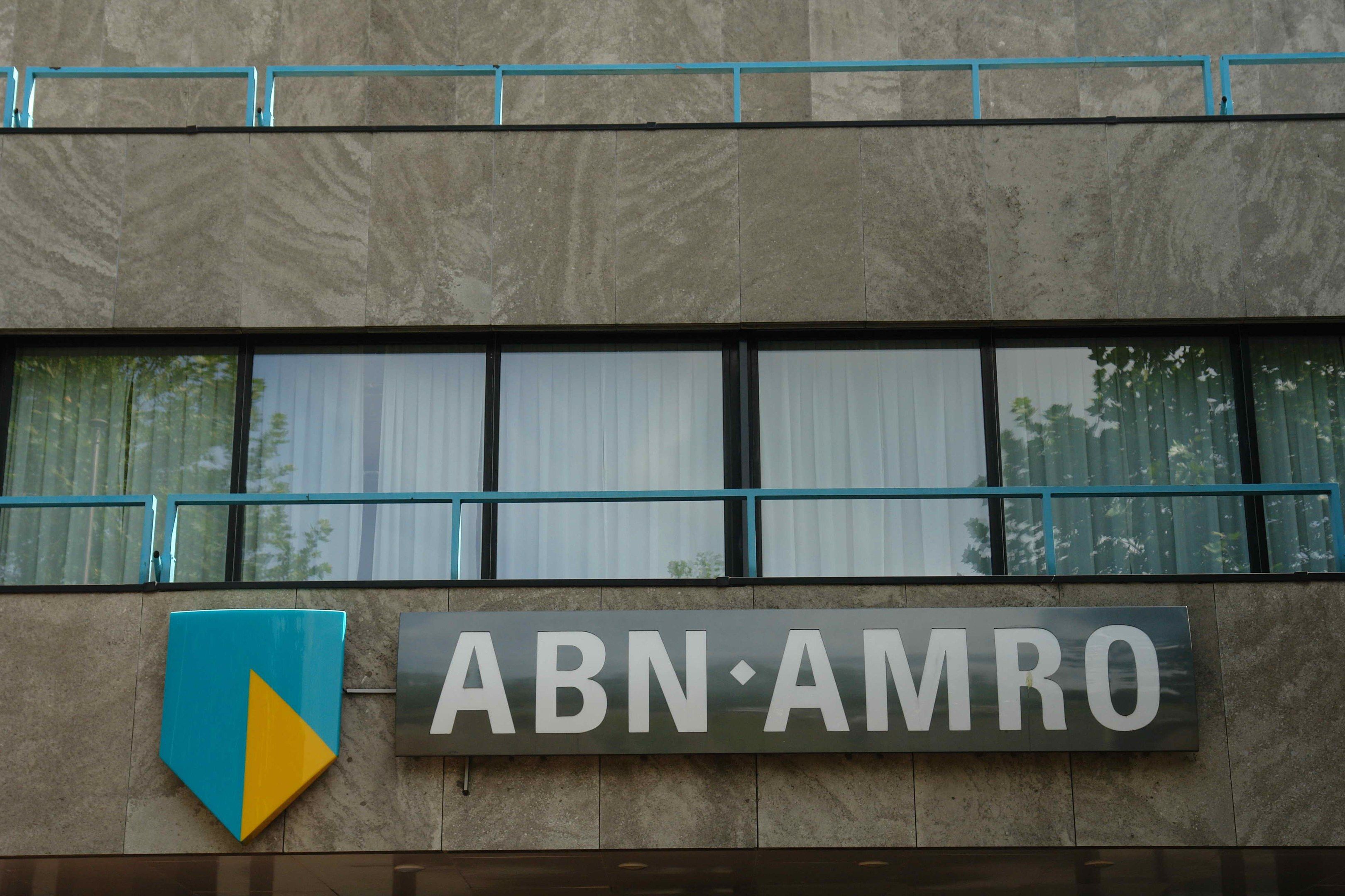 The image shows a building with a sign that reads "ABN AMRO" on the side of it, along with a board...