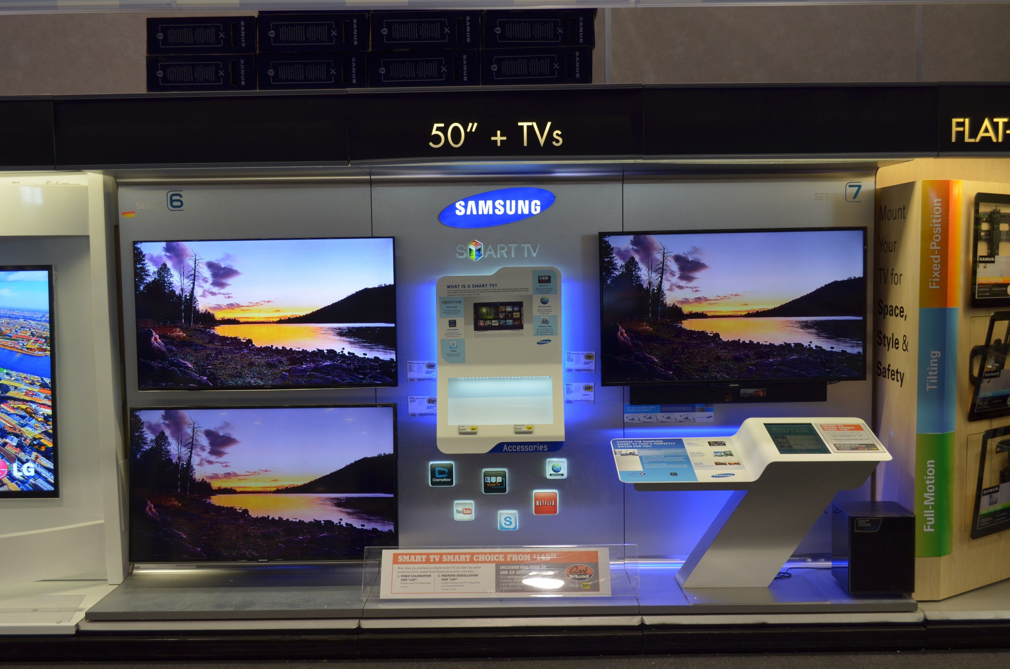 The image shows a store with a variety of televisions on display, including a Samsung Smart TV and...