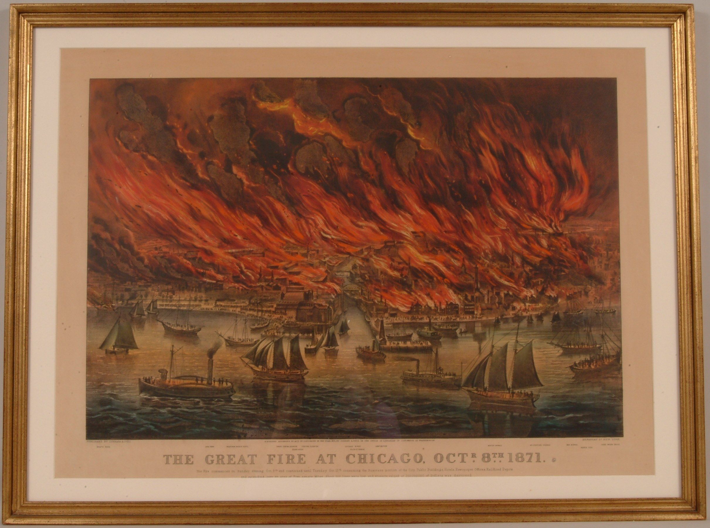The image shows a photo frame on the wall with a picture of boats on the water engulfed in flames....