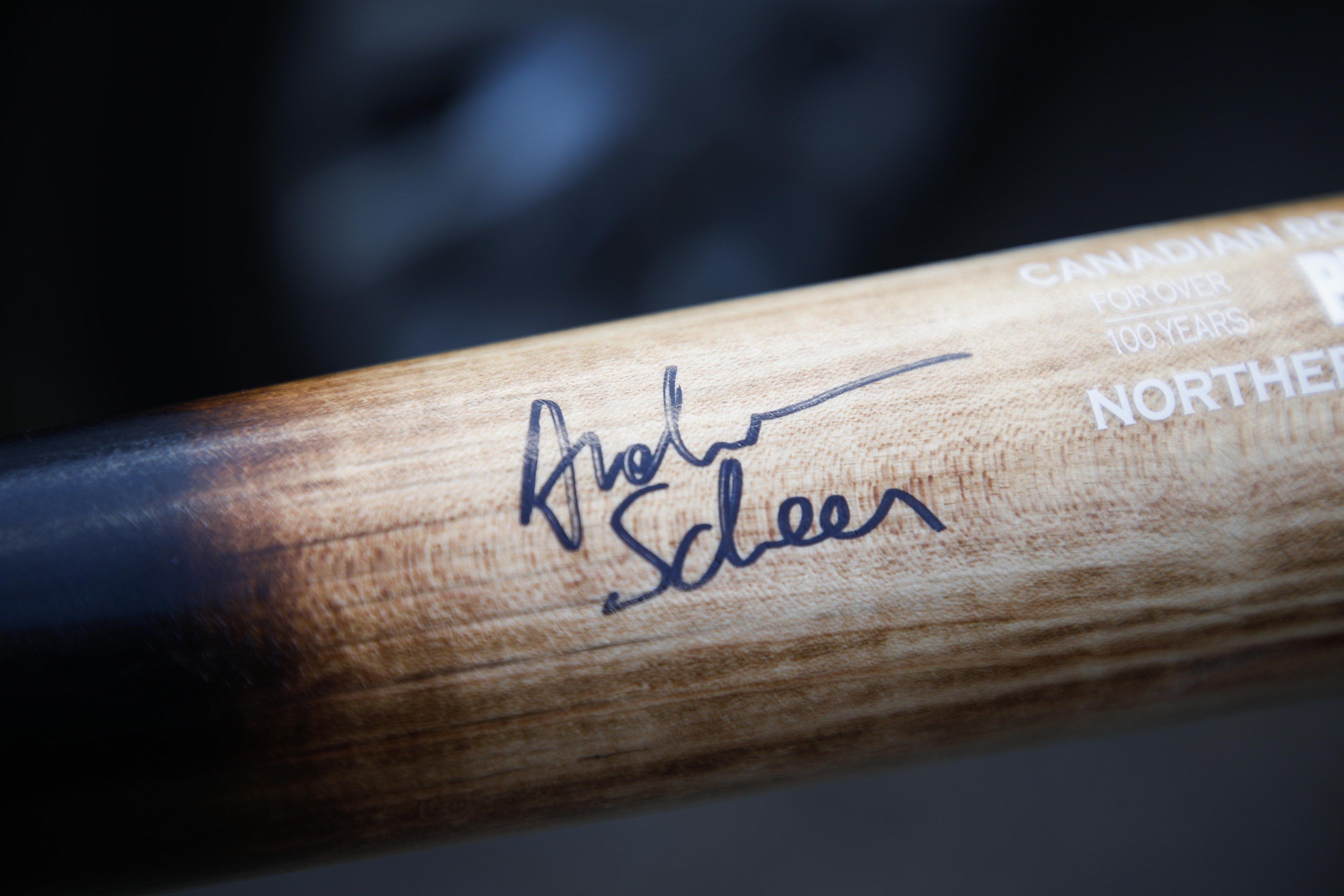 The image shows a close up of a hockey stick with a signature on it. The stick is made of wood and...